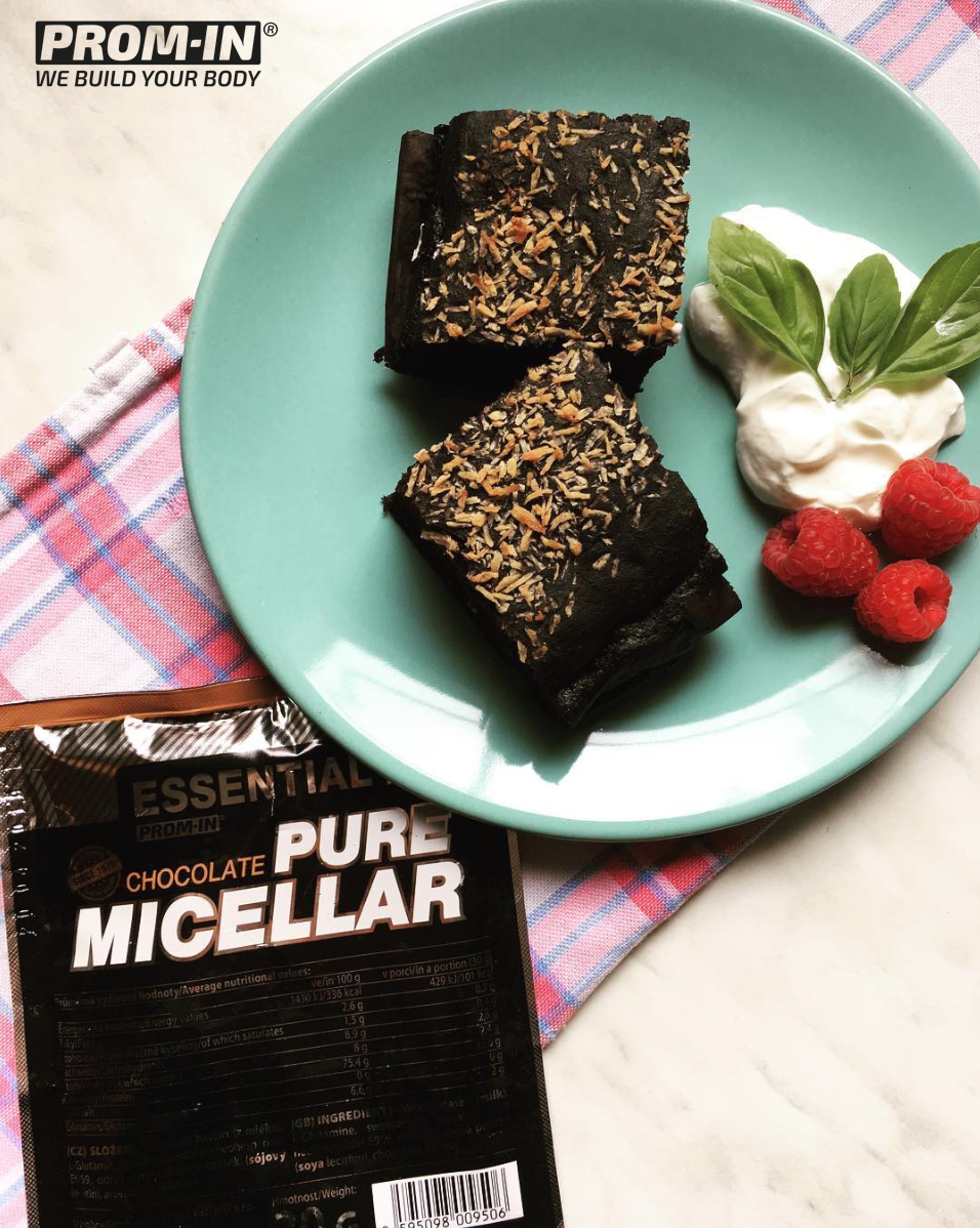 Lifestyle fotografia s mentolovo zeleným tanierom obsahujúcim dva čokoládové brownies posypané orechmi, vedľa maliny a šľahačka s lístkami mäty. Dole je balenie Essential Pure Micellar v čokoládovej príchuti s logom Prom-in "We Build Your Body" na károvanom obruse.
