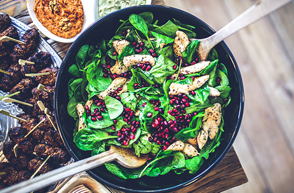 Ilustračná fotografia zdravého jedla. Miska plná špenátu s kuracím mäsom a granátovým jablkom.